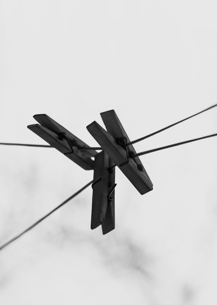 Black and white close-up of wooden clothespins on a wire outdoors.